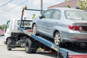 A car being towed on a flatbed truck, indicating a towing service to avoid further issues.